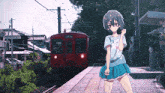 a girl is standing in front of a red train that says ' railway station ' on it
