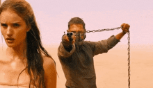 a man is pointing a gun at a woman while holding a chain
