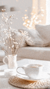a cup of coffee sits on a table next to a vase of flowers with the words good written above it