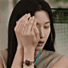a woman is covering her face with her hands and wearing a watch