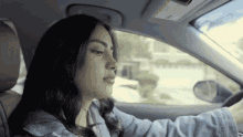 a woman is sitting in the driver 's seat of a car and looking out the window