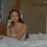 a woman is laying in bed talking on a telephone