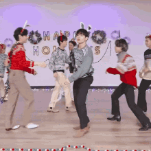 a group of people are dancing in front of a sign that says " happy holidays "