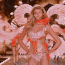 a woman wearing a corset and wings is walking down a runway