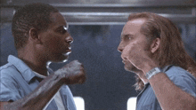 two men in blue shirts are fighting with their fists in the air