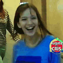 a girl in a blue shirt is laughing in front of a sign that says jugate con crisis