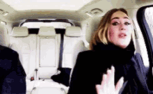 a woman is sitting in the back seat of a car talking to someone .