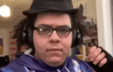 a man wearing a hat , headphones and glasses is making a funny face .