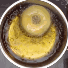 a donut is being cooked in a pan of oil