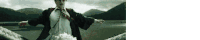 a man in a suit and tie is standing in front of a lake .