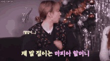 a woman is sitting on a couch in front of a christmas tree and talking in a foreign language .