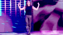 a woman is standing on a stage with her arms outstretched in front of a large screen .