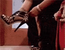 a woman is putting on a pair of high heels in a room .