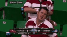 a man sits in a stadium watching a game between harvard and arizona ..