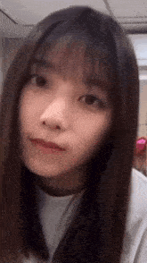 a close up of a woman 's face with long hair and a white shirt .