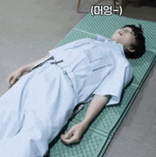 a man in a hospital gown is laying on a green mattress