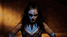 a woman with face paint on her face is wearing a blue and gold outfit .