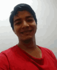 a man in a red shirt is smiling and looking at the camera .