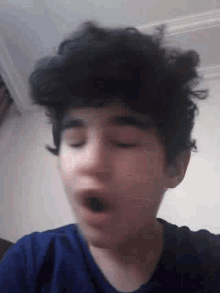 a young boy with curly hair is yawning with his mouth open .