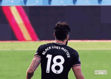 a soccer player is wearing a black jersey with the number 18 on it