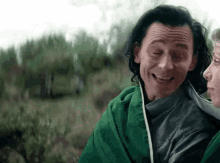 loki is wrapped in a green blanket and smiling .