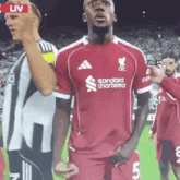 a soccer player wearing a red shirt that says standard chartered