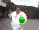 a fat man in a white karate uniform is running with a green circle in his chest .