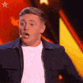 a man with a surprised look on his face stands in front of a microphone with a star in the background