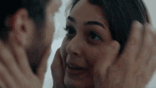 a man is touching a woman 's face in a close up of their faces .