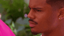 a close up of a man 's face with a pink shirt on