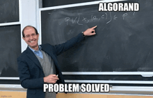 a man in a suit is pointing at a blackboard with a math problem written on it .