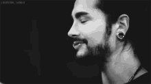 a black and white photo of a man with a beard and piercings .