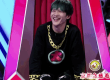 a man with green hair and a gold chain around his neck is laughing