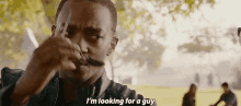 a man with a mustache is smoking a cigarette in a park .