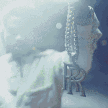 a close up of a person wearing a necklace with a letter r on it