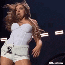 a woman in a white top and white shorts is dancing on stage .