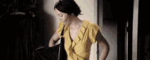 a woman in a yellow ruffled top is holding a black purse .