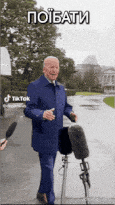 a man in a blue coat stands in front of a microphone with a caption that says " poibati "