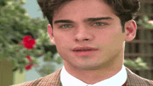 a close up of a man 's face with a plaid jacket on