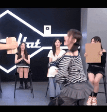 a group of women sitting in front of a sign that says that