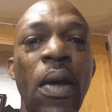 a bald man is crying with tears running down his face .