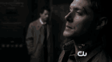 a close up of a man 's face with a tv to talk about cw logo