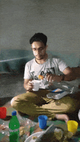 a man sits on the floor with a sprite bottle nearby