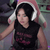 a woman wearing headphones and a black shirt that says " black stones "
