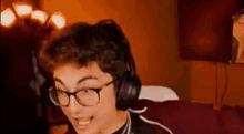 a young man wearing glasses and headphones is sitting in front of a computer .