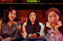 three women are sitting next to each other and one of them is making a face