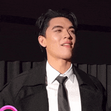 a man in a suit and tie is smiling and looking away from the camera