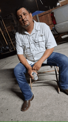 a man is sitting on a chair with a can of beer in his hand