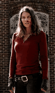a woman in a red shirt is standing in front of a brick door