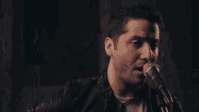 a man singing into a microphone while wearing a black leather jacket